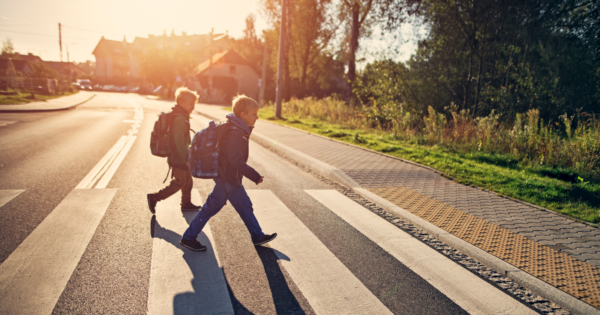 Two children crossing the road using a zebra crossing.