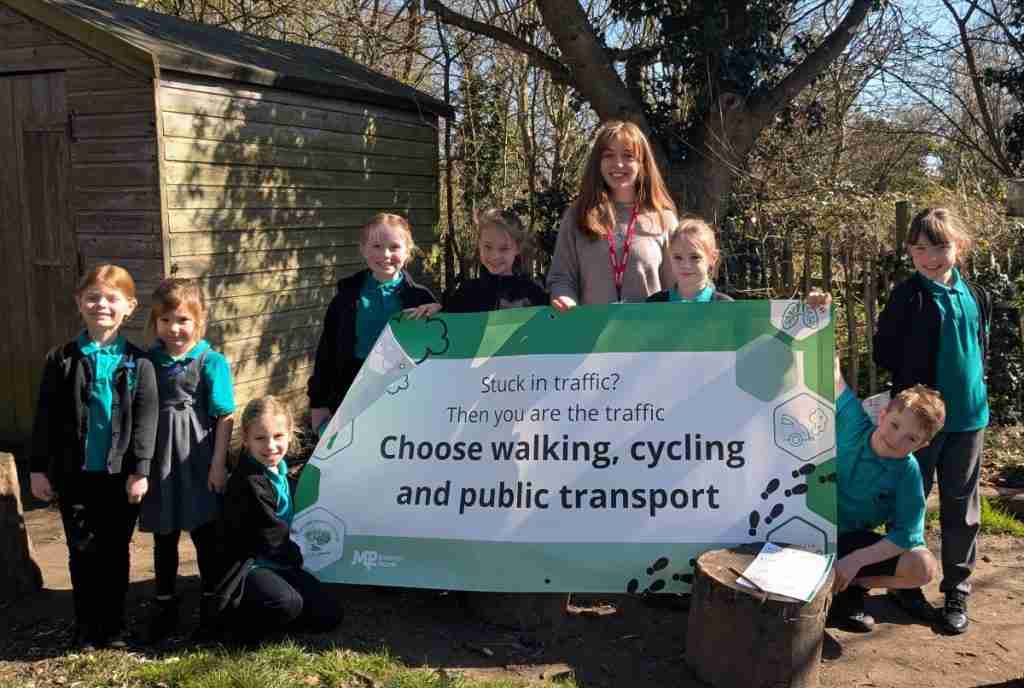 Children holding up a banner saying "Choose walking, cycling and public transport".