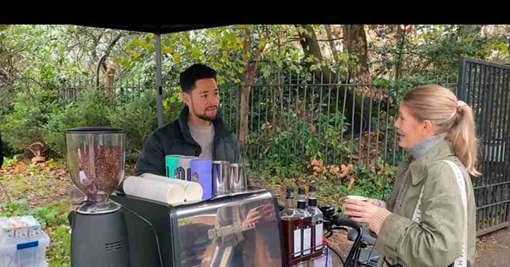 Man and woman chat under an umbrella near a cargo bicycle