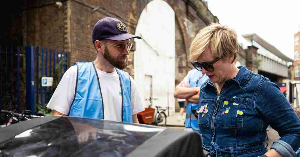 Woman in Denim clothes talks with man in a cap by a cargo bicycle