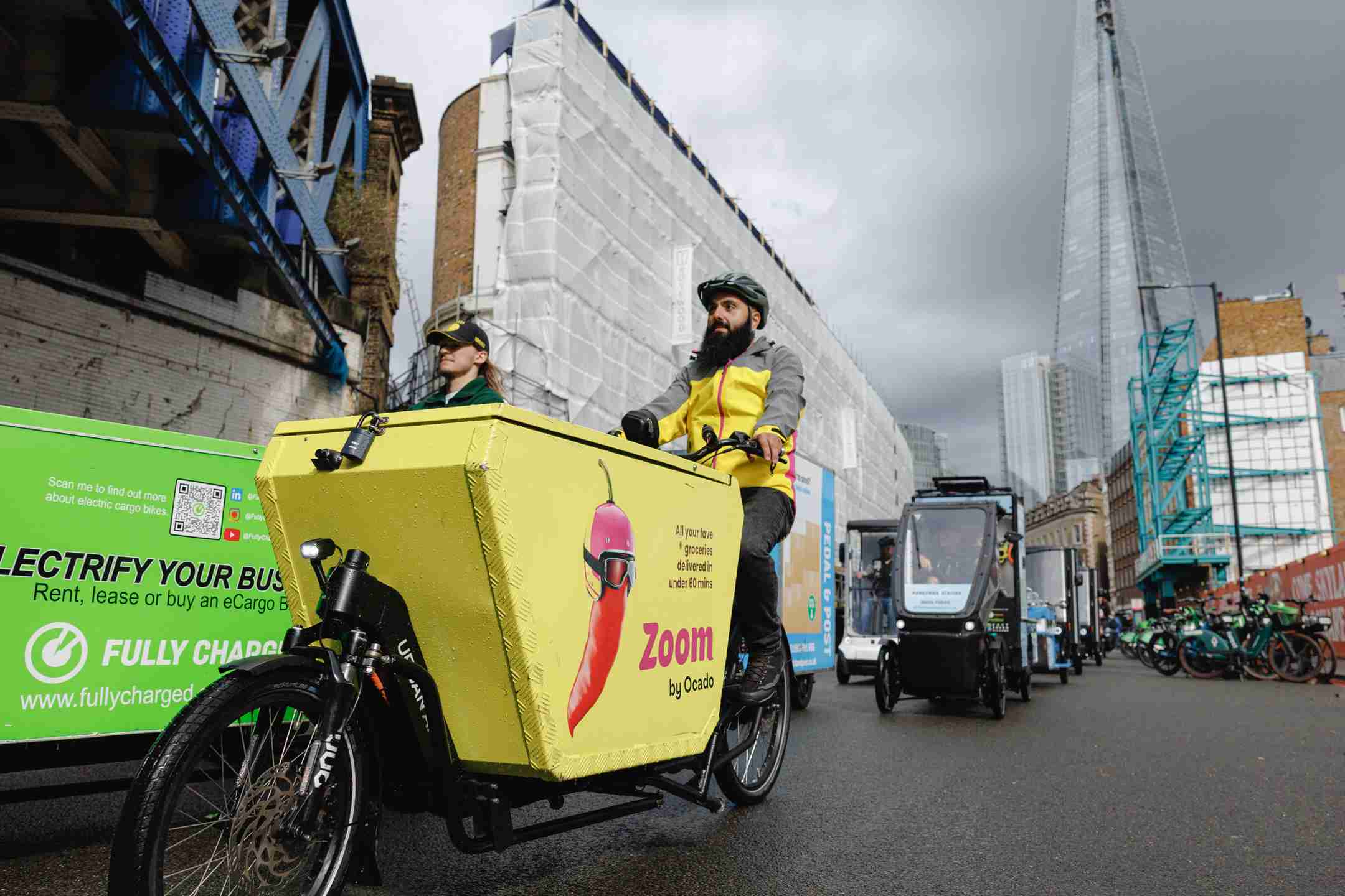 Cargo Bike rider dressed in a yellow jacket. The cargo bike is yellow and branded with a red chilli.
