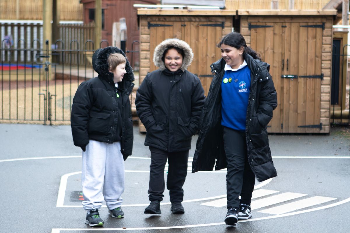 In the playground Three children walking and talking together at school.